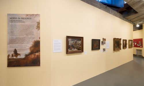 Eye-level view of exhibition intro text wall with oblique view of wall with five paintings and two didactic text panels